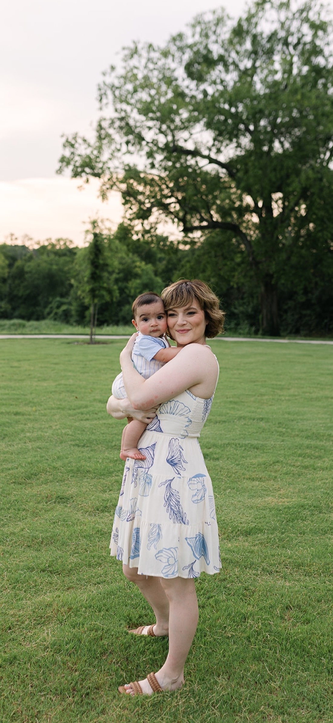 Rachel holding her baby in a park at sunset