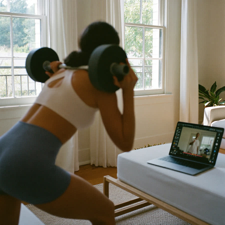 A laptop and dumbbells set up for a home workout